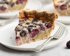 there is a piece of pie on the plate next to some berries and a fork