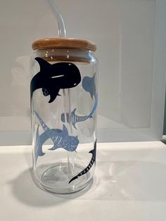 a glass jar with a wooden lid and an image of sharks on it is sitting on a table