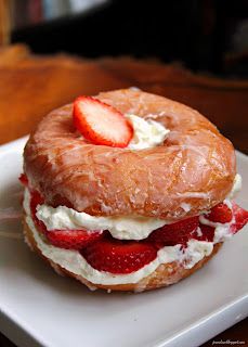 a bagel with cream cheese and strawberries on it sitting on a white plate