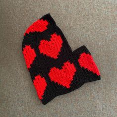 a crocheted hat with red hearts on it