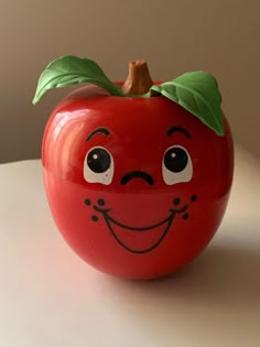 a red apple with a face painted on it's side sitting on a table