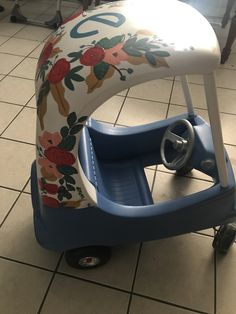 a child's tricycle with flowers painted on the side and wheels attached to it