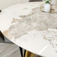 a white marble dining table with gold legs and two vases on the end tables