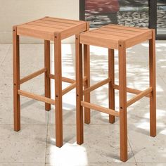 two wooden stools sitting next to each other on a tile floor in front of a building