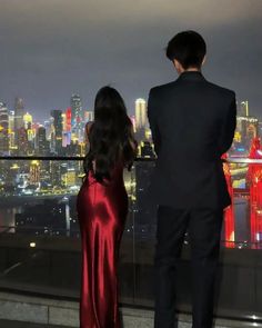 a man and woman looking out over the city at night