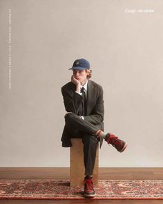 a young woman sitting on top of a wooden block wearing a hat and jacket with her legs crossed