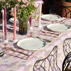 the table is set with plates, silverware and flowers in vases on it