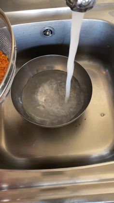 a metal sink filled with lots of water next to a bowl full of carrots