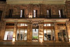 an old building with many windows and balconies lit up at night in the city