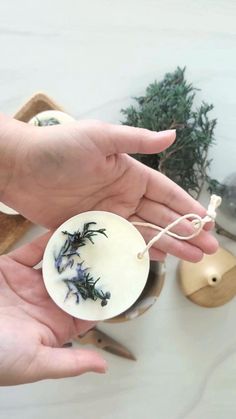 two hands are holding a small bowl with flowers on it