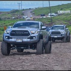 two large trucks driving down a dirt road