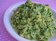 a white bowl filled with green food on top of a purple tablecloth covered table