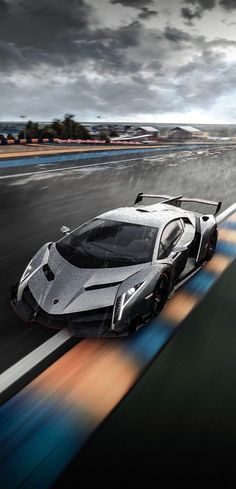 a white and black sports car driving on a track with clouds in the background at night