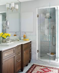 a bathroom with two sinks, a shower and a rug on the floor in front of it