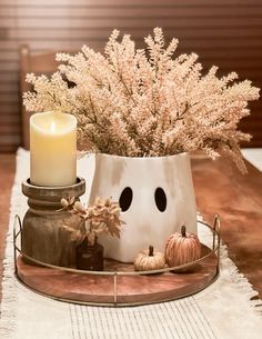 a white vase filled with flowers next to a lit candle on top of a table