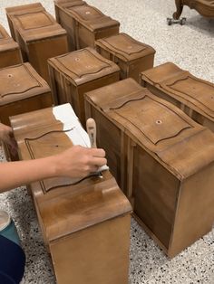 a person is sitting on the floor with many wooden boxes in front of them and writing