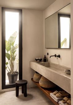 a bathroom with a sink and mirror next to a plant in a pot on the floor