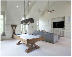 a pool table in the middle of a living room with two couches and a flat screen tv