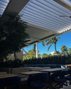 an outdoor dining area with tables and chairs under a covering over the water's edge