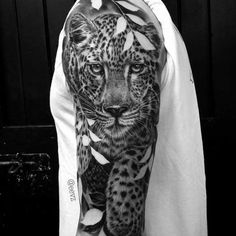 a man's arm with a black and grey tattoo on it, depicting a leopard