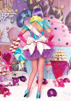 a woman in a dress and heels standing next to a table with cupcakes on it