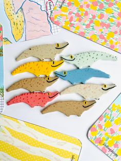 paper cutouts of fish are displayed on a white surface with colorful patterns and designs