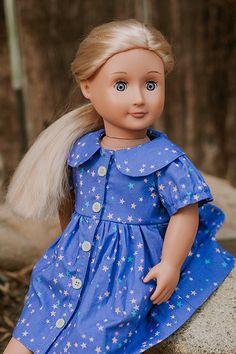 a doll with blonde hair sitting on a rock