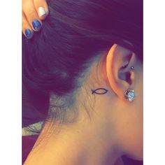 a woman's left ear has a small eye tattoo on the back of her right ear