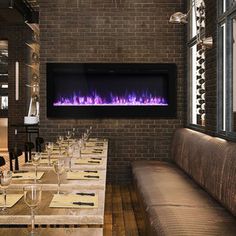 a long table with place settings and wine glasses on it in front of a brick wall