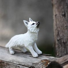 a small white dog figurine sitting on top of a piece of wooden plank