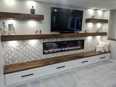 an entertainment center with built - in fireplaces and floating shelves on the wall, along with decorative vases