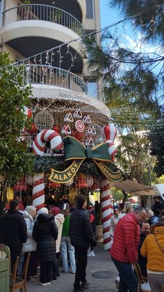 many people are walking around in front of a building decorated with christmas decorations and candy canes