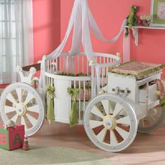 a baby's room with pink walls, white crib and wooden carriage in the foreground