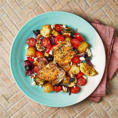 a white plate topped with chicken, potatoes and tomatoes on top of a pink napkin