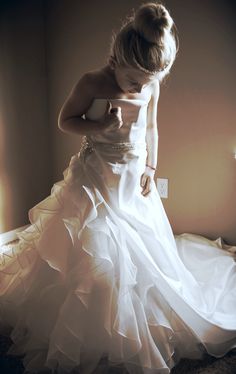 a woman in a white dress is standing on a bed with her hands behind her back