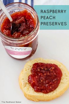 a jar of raspberry peach preserves next to a cookie