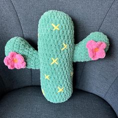 a stuffed cactus sitting on top of a blue chair with pink flowers in it's arms