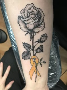 a black and white rose with a yellow ribbon on the wrist is shown in this image