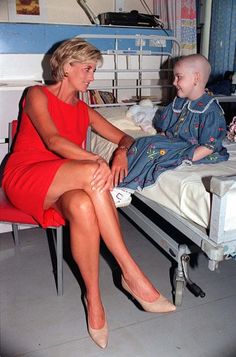 a woman in a red dress sitting on a hospital bed next to a little boy