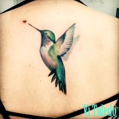 a hummingbird tattoo on the back of a woman