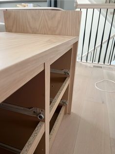 a wooden table with drawers on top of it in front of a stair case and railing