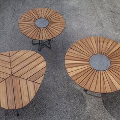 three wooden tables sitting on top of cement ground next to each other with circular tops