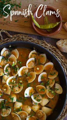 a pan filled with clams and garnished with parsley next to bread