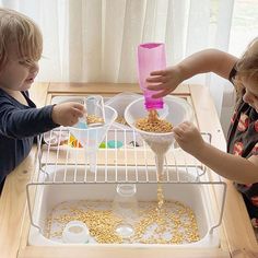 two children are playing with food in the fridge while one child is pouring it into another