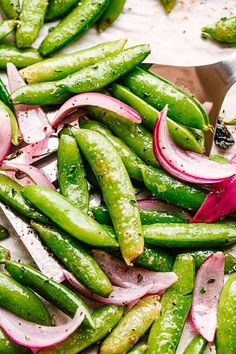 green beans and onions are being chopped on a cutting board with a large metal spoon