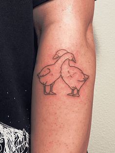 a man with a tattoo on his arm that has two birds on it and is standing next to each other