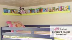 a child's bedroom with bunk beds and bookshelves on the wall above them