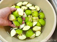 someone is picking up some green apples in a bowl