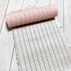 a roll of pink fabric sitting on top of a white wooden floor