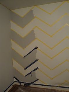 the wall is painted with yellow and white chevrons in an otherwise empty room